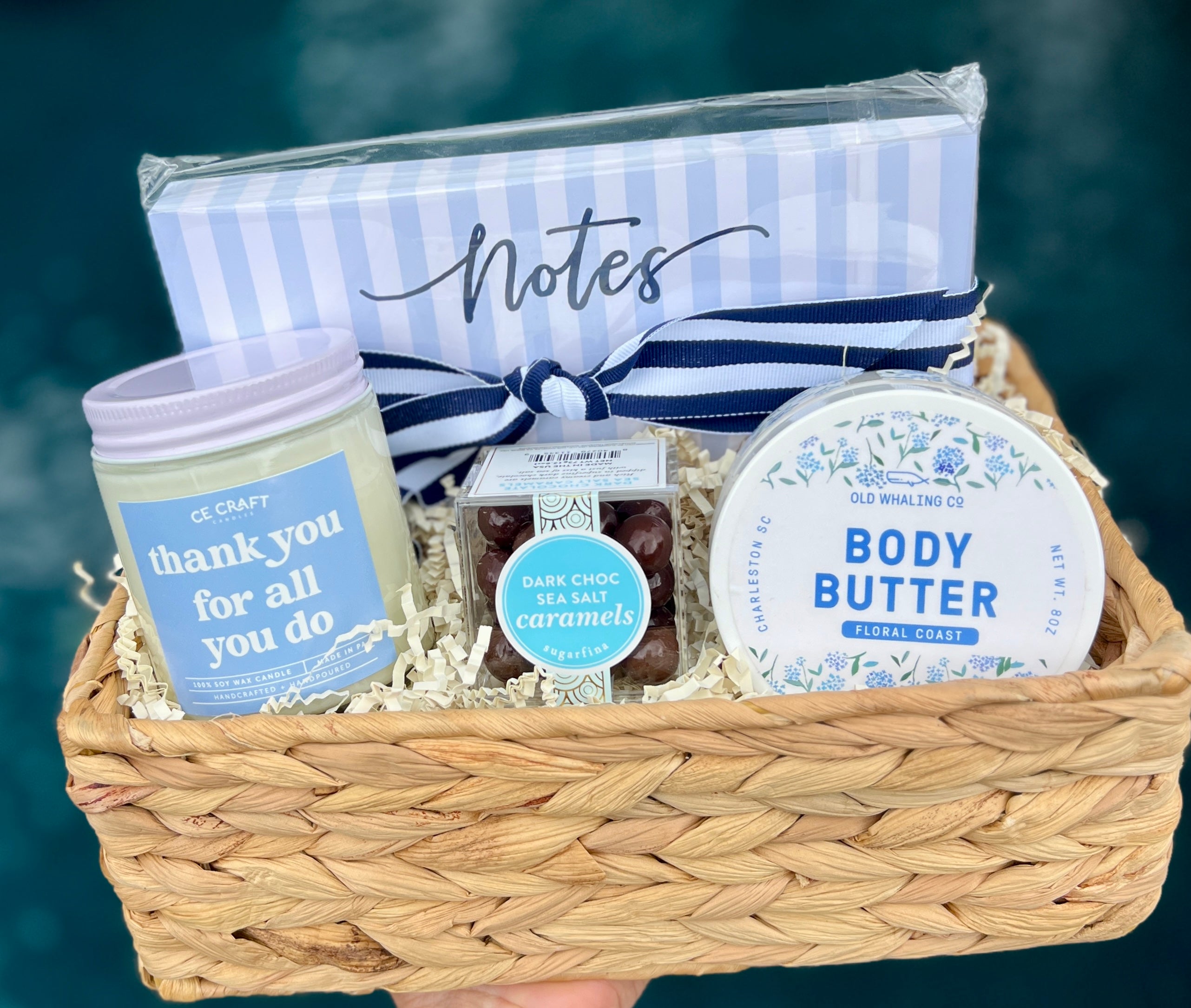 Gift basket with body butter, candles, and a notebook on a blurred background